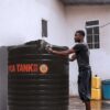 Cylindrical water tank Kenya on concrete base outside home